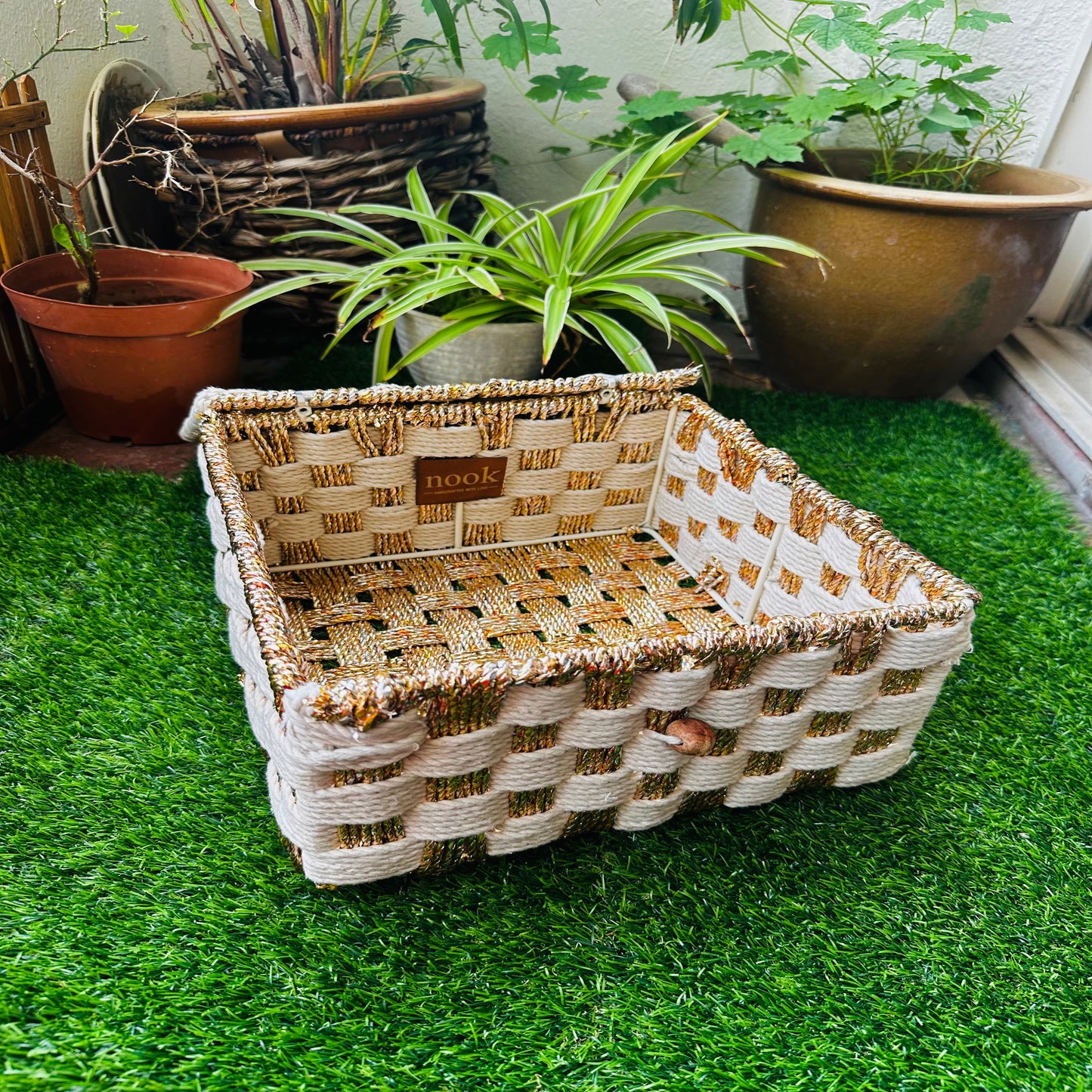 Woven basket on a green grassy surface with plants in the background