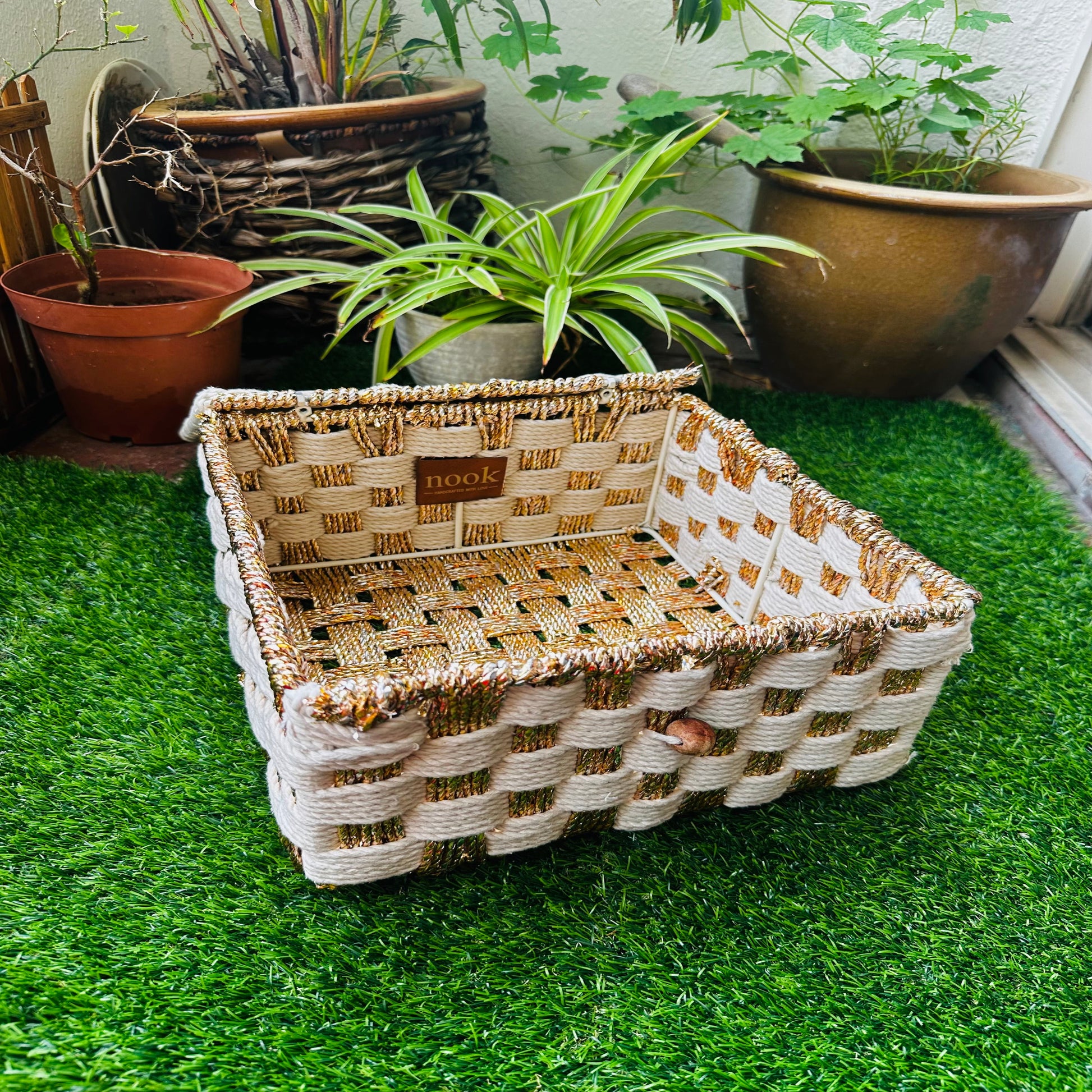 Woven basket on a green grassy surface with plants in the background